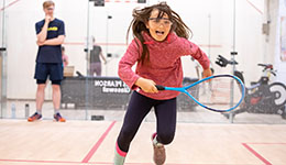 A girl running on a squash court